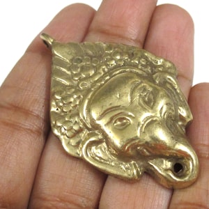 Puede incluir: Colgante de metal dorado con forma de cabeza de elefante. El colgante presenta detalles como los ojos, la trompa y las orejas. Tiene un lazo en la parte superior para colgar, ideal para un collar.