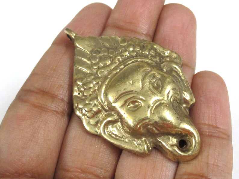 Puede incluir: Colgante de metal dorado con forma de cabeza de elefante. El colgante presenta detalles como los ojos, la trompa y las orejas. Tiene un lazo en la parte superior para colgar, ideal para un collar.