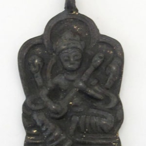 May include: A dark, antique-style pendant featuring a seated figure playing a stringed instrument. The pendant has an arched top and a loop for hanging. The figure is surrounded by ornate details, and the overall color is a dark bronze.