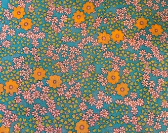 May include: A teal fabric with a repeating pattern of pink and orange flowers. The flowers are stylized and have a retro look.