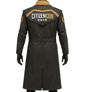 May include: A long, dark gray coat with a gold and black design on the shoulders and back. The text "CITIZENCON - 2948" is displayed on the back. The coat has a high collar and long sleeves, and is worn with black gloves.
