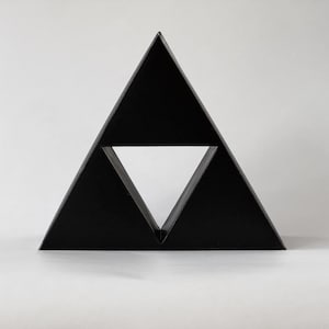 May include: A black triangular geometric shape with a smaller triangle cut out of the center.
