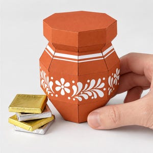 以下が含まれることがあります： テラコッタ色の紙製クラフトポット。白い花柄と水平のストライプが施され、八角形のファセット形状をしています。ポットの横には、金と銀のホイルで包まれた4つの小さな正方形のチョコレートがあります。テキスト：DIGITAL DOWNLOAD PDF & SVG FILES NO PHYSICAL ITEM。