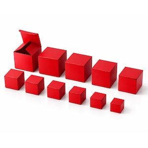 May include: A collection of red square gift boxes of varying sizes, arranged on a white surface. One box is open, revealing its interior. The boxes are evenly spaced, creating a visually appealing display.