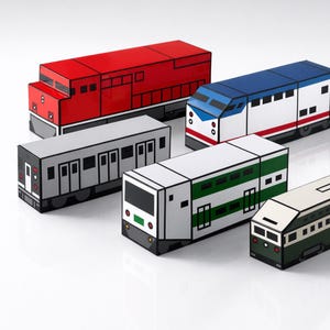 Peut inclure: Plusieurs trains jouets colorés, rouges, bleus, blancs, verts et gris. Les trains sont conçus avec des formes géométriques et des contours noirs, ressemblant à différents types de locomotives et de wagons. Les trains sont disposés sur une surface blanche.