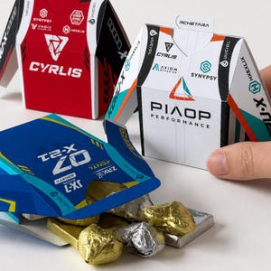 Op de afbeelding: Drie kleine papieren doosjes met grafische ontwerpen en logo's zoals Rchetara, Cyrlis en Piop Performance. Eén blauwe doos is geopend en toont goud- en zilverkleurige folie-verpakte items. Tekst onderaan: DIGITAL DOWNLOAD PDF FILE NO PHYSICAL ITEM.