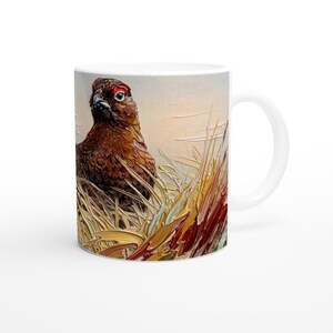 May include: White ceramic mug featuring a detailed painting of a pheasant in a field of tall grass. The bird has brown feathers and a red eye. The artwork is rendered in an impressionistic style, with visible brushstrokes.