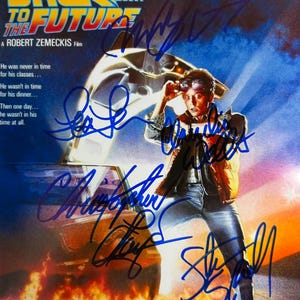 May include: A movie poster for "Back to the Future" featuring the film's title in bold, colorful lettering. The poster includes an image of a person with sunglasses and a car. The poster has multiple signatures in blue ink.