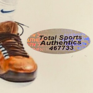 Puede incluir: Primer plano de una zapatilla deportiva marr&oacute;n y naranja con cordones negros. El logotipo blanco de Nike est&aacute; en el fondo. Tambi&eacute;n es visible una pegatina de Total Sports Authentics.