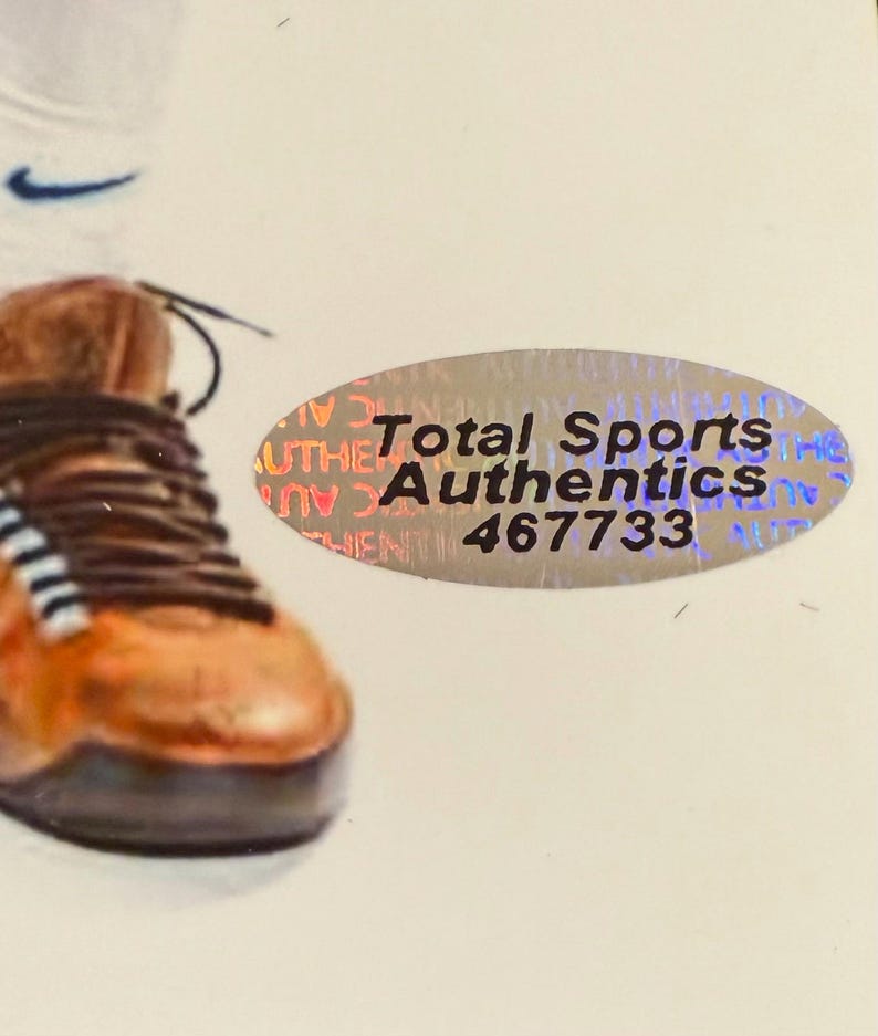 Puede incluir: Primer plano de una zapatilla deportiva marr&oacute;n y naranja con cordones negros. El logotipo blanco de Nike est&aacute; en el fondo. Tambi&eacute;n es visible una pegatina de Total Sports Authentics.
