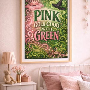 May include: A framed art print with the text "PINK GOES GOOD WITH GREEN" in a whimsical design. The artwork features pink and green colours, a witch's hat, and a crown. The print is displayed in a bedroom setting with a bed and nightstand.