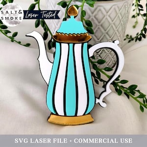 May include: A teal and white striped teapot with a gold lid and base. The teapot has a heart-shaped handle and a spout. The teapot is sitting on a white surface.