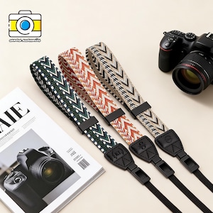 Könnte beinhalten: Drei gemusterte Kameragurte in Grün, Orange und Beige mit schwarzen Anschlüssen und Lederenden. Die Gurte haben geometrische Muster. Im Hintergrund ist eine schwarze Kamera zu sehen, zusammen mit einer Zeitschrift und einem Logo mit der Aufschrift "camera accessories".