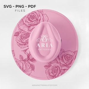 May include: A pink hat with a matching brim, featuring a rose pattern and the text "SVG - PNG - PDF FILES". The hat has a central, oval-shaped crown with the "ARIA PATTERNS" logo. The website address ARIAPATTERNS.ETSY.COM is at the bottom.