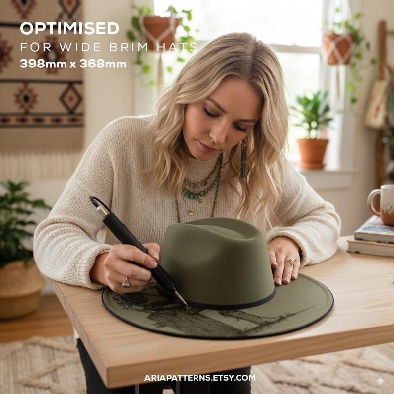 May include: An olive green wide brim hat is being detailed with a black tool. The hat sits on a wooden table. The text "OPTIMISED FOR WIDE BRIM HATS 398mm x 368mm" is visible at the top. The website address "ARIAPATTERNS.ETSY.COM" is at the bottom.