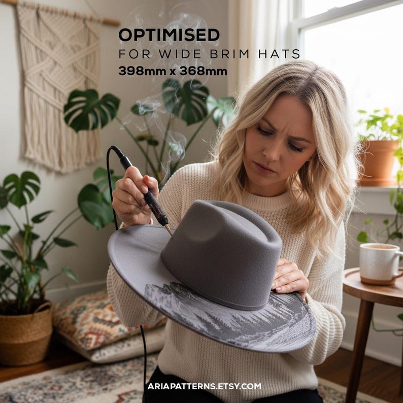 May include: A woman working on a gray wide-brimmed hat with a wood-burning tool. The hat has a mountain and tree design. The text on the image reads "OPTIMISED FOR WIDE BRIM HATS 398mm x 368mm" and "ARIAPATTERNS.ETSY.COM".
