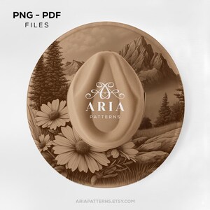 May include: A tan cowboy hat with a landscape design. The hat features a mountain scene and floral elements. The text "ARIA PATTERNS" is displayed on the hat. The image also includes the text "PNG - PDF FILES" and the website address "ARIAPATTERNS.ETSY.COM".