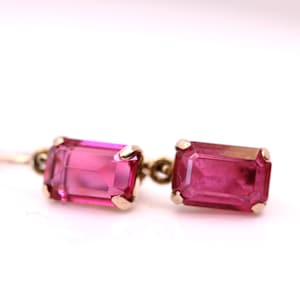 Peut inclure: Une paire de boucles d'oreilles vintage avec des pierres précieuses rectangulaires magenta serties dans du métal doré. Les boucles d'oreilles ont un design classique, parfaites pour ajouter une touche de couleur et de sophistication.
