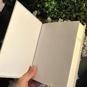 Op de afbeelding: Een blanco, wit, met linnen bekleed dagboek met een cr&egrave;mekleurige binnenkant. Het dagboek is open om de lege pagina's te laten zien.
