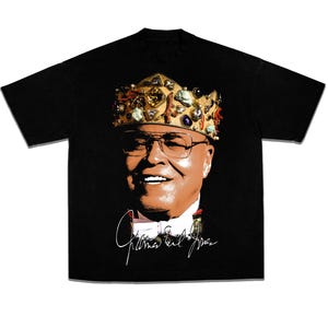 Puede incluir: Camiseta negra con un retrato de un hombre que lleva una corona adornada con joyas y una firma que dice "James Earl Jones".