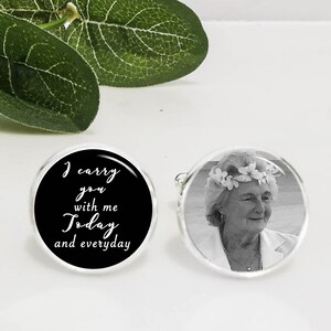 May include: A pair of cufflinks, one with a black background and white text that reads "I carry you with me today and everyday", and the other with a black and white photo of a woman wearing a flower crown.