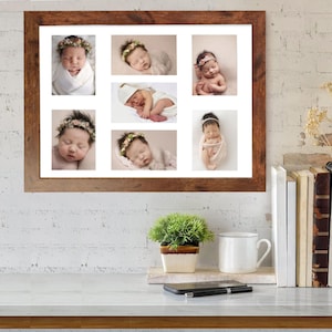 May include: A framed collage featuring seven photographs of sleeping newborns. Each baby is adorned with floral headbands or wrapped in soft blankets. The frame is a warm, dark brown, and the overall aesthetic is soft and serene.