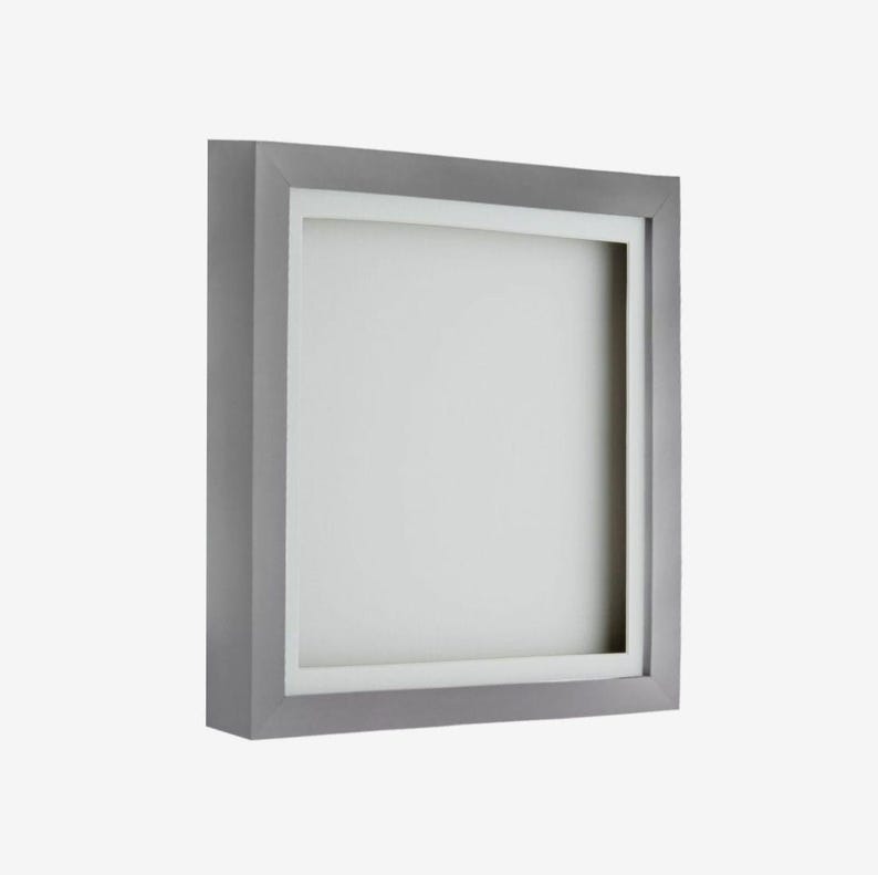May include: A silver picture frame with a white mat. The frame is square and has a simple design.
