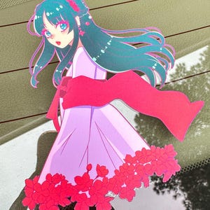 May include: A sticker featuring a cartoon anime girl with long teal hair wearing a pink dress and a red scarf. The girl is surrounded by pink flowers.