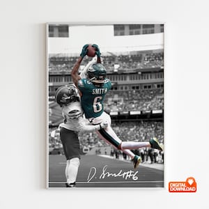 May include: A framed black and white photograph of a football player in a teal jersey catching a football. The player is wearing a helmet and the number 6 is visible on the jersey. The background is a stadium filled with spectators. The player's signature is at the bottom.