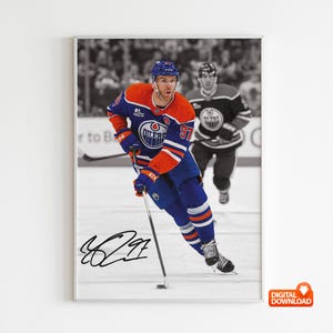 May include: A framed print featuring a color image of a hockey player in an Oilers jersey, number 97, skating on the ice. The background is in black and white, with another player in the background. The print includes a signature.