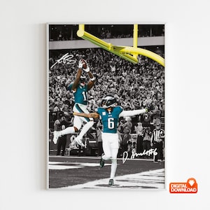 Puede incluir: Impresión en blanco y negro enmarcada con dos jugadores de fútbol americano en acción. Uno salta para atrapar el balón, el otro celebra. Firmas y el número 6 en las camisetas.