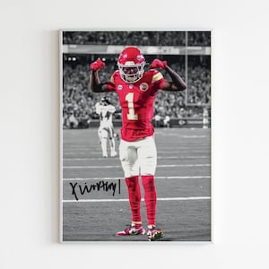 May include: Framed print of a football player in a red uniform with the number 1, celebrating on a field. The background is in black and white, with the player's uniform in color. The print includes a signature.