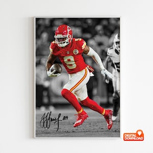 May include: A framed print of a football player in a red uniform, number 9, running with the ball. The background is monochrome, with the player's uniform in colour. The player's signature is at the bottom of the print.
