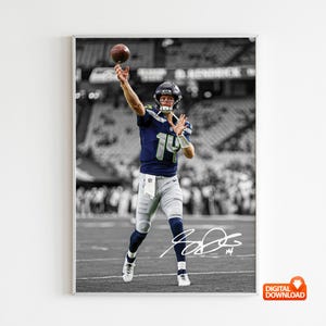 May include: A framed digital print showing a football player throwing a brown football. The player is wearing a navy blue and green uniform with the number 14. The background is in black and white, with the player in colour.