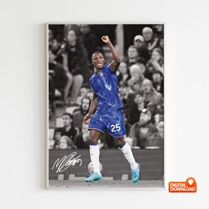 May include: A framed digital download print featuring a soccer player in a blue uniform with the number 25, celebrating a goal. The background is a black and white image of the crowd. The print includes a signature.