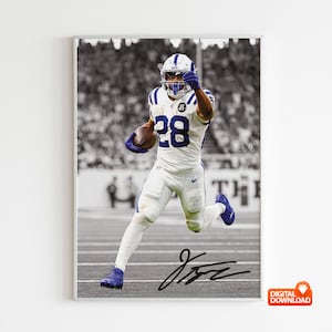 May include: Black and white framed print of a football player in a white uniform with blue accents, number 28, and a helmet. The player is running with the ball, and the image includes a signature.