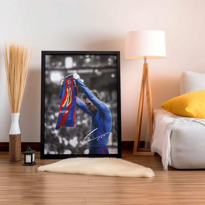 以下が含まれることがあります： サッカー選手が青と赤のユニフォームを掲げている白黒写真。ユニフォームには10番の数字が書かれている。選手は青いユニフォームを着ており、ユニフォームを見ている。写真は黒い額縁に入っている。