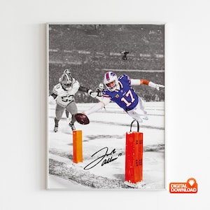 May include: Framed black and white print of a football game. A player in a blue and white uniform dives for a football, with another player in a white uniform running behind him. The print includes the player's signature and the number 17.
