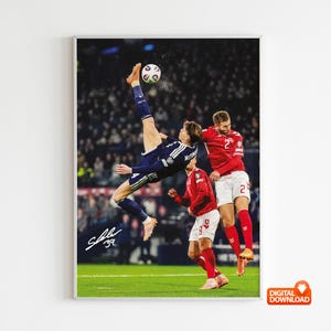 May include: A framed print depicting a soccer match. A player in a blue and white kit performs a bicycle kick, with two players in red kits attempting to block. The background shows a stadium full of spectators.