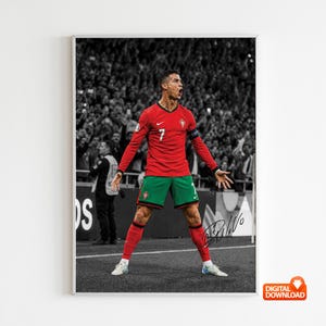 May include: A vertical poster featuring a footballer in a red long-sleeve jersey and green shorts with the number 7, standing on a pitch with arms outstretched. The background is a black and white crowd, and a black signature is visible on the right.