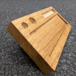 May include: A wooden tray with a rectangular shape and a beveled edge. The tray has three small circular indentations and a long rectangular indentation. The tray is made of light brown wood.