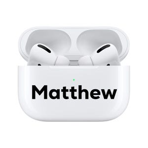 Puede incluir: Auriculares inalámbricos blancos en un estuche de carga. El estuche es blanco con el nombre "Matthew" impreso en negro. Los auriculares están en el estuche abierto, listos para usar.