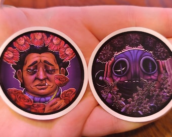 May include: Two round stickers with unique illustrations. One features a person with a floral crown and roses, the other a purple creature. Both have a white border and are set against a purple background.