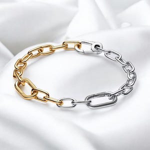 Puede incluir: Una pulsera de cadena bicolor con eslabones dorados y plateados. La pulsera presenta una mezcla de eslabones ovalados y rectangulares, creando un diseño moderno. El cierre es plateado y asegura la pulsera.