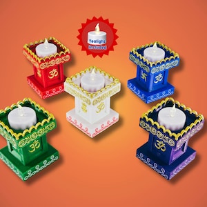 May include: A collection of colorful candle holders, each with a white tea light. The holders are painted in red, green, blue, white, and purple, with gold accents and decorative patterns. The text "Tealight included" is visible.