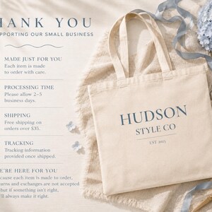 May include: A cream-colored tote bag with the text "HUDSON STYLE CO" and "EST 2025" printed in blue. The bag is on a cream-colored cloth, with blue flowers and a pair of gold scissors. The text "THANK YOU" is at the top.