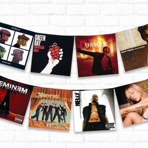 May include: A collection of eight different music album covers, including albums by Gorillaz, Green Day, Usher, Ricky Martin, Eminem, NSYNC, Nelly, and Christina Aguilera. The covers are displayed in a row, hanging from a string.