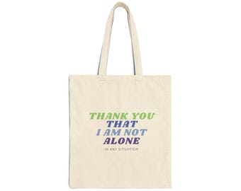 May include: A beige tote bag with the text "Thank You That I Am Not Alone In Any Situation" printed in green, blue, and purple.