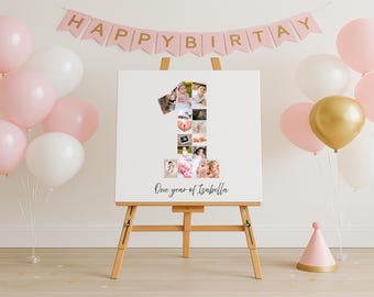 May include: A wooden easel displays a white canvas with a collage of photos in the shape of the number one. The canvas is inscribed with "One year of Isabella". Pink and white balloons and a banner that says "HAPPY BIRTHDAY" decorate the background.
