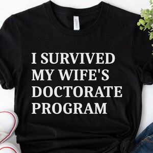 Camiseta "Sobreviví al programa de doctorado de mi esposa", Camiseta de doctorado para esposas, Regalo divertido de graduación de doctorado, Camiseta de apoyo para esposos, Camiseta para fiesta de doctorado